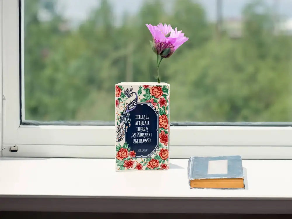 Navy ceramic book vase with red floral border and navy panel by Decorbites beside a blue book on Tampa Home & Garden Store