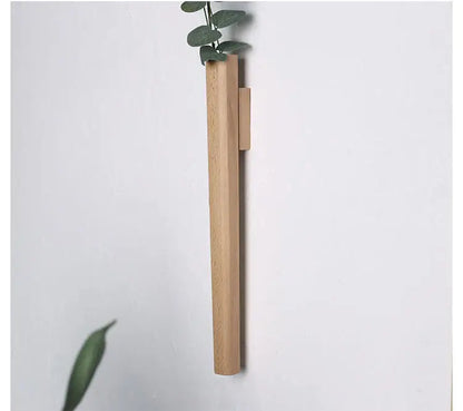 Dark wood wall vase by Decorbites, vertical wall-mounted wooden vase with leafy stem on white wall on Tampa Home & Garden Store
