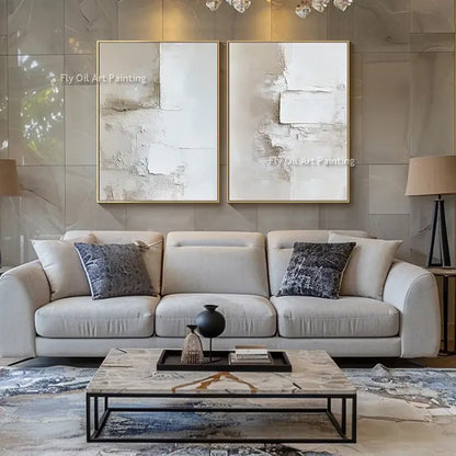Two-panel beige and white abstract canvas oil paintings with gold frames above a neutral sofa on Tampa Home & Garden Store