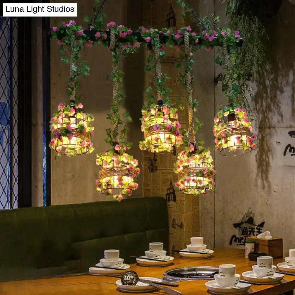 Five black cage island pendant lights with flowers over a dining table by Luna Light Studios on Tampa Home & Garden Store