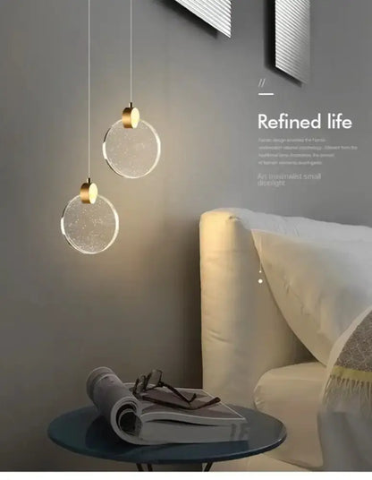 Two modern gold LED crystal pendant lights with glass discs over a bedroom nightstand on Tampa Home & Garden Store