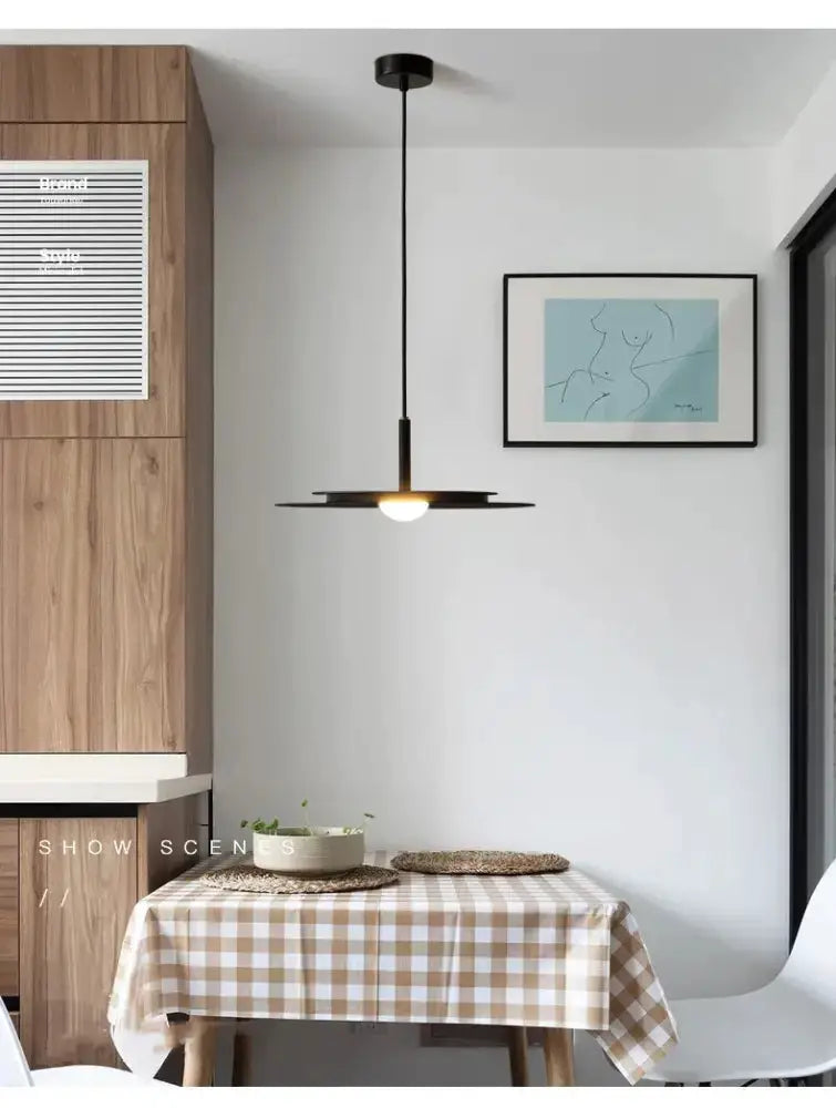 Decorbites minimalist black flying saucer pendant light over a checkered dining table on Tampa Home & Garden Store