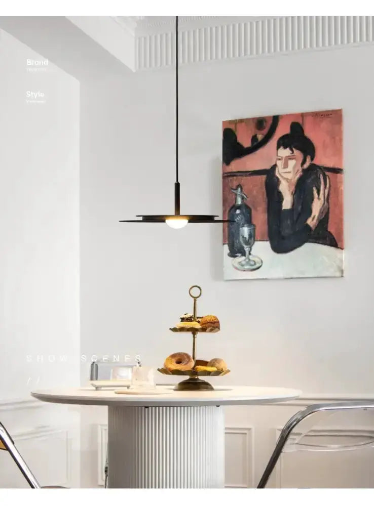 Minimalist black flying saucer pendant chandelier over a white dining table in a dining room on Tampa Home & Garden Store