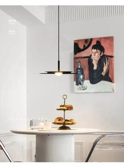 Minimalist black flying saucer pendant chandelier over a white dining table in a dining room on Tampa Home & Garden Store