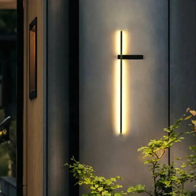Outdoor wall light sconce with vertical LED bar and subtle crossbar in black metal, warm glow on Tampa Home & Garden Store
