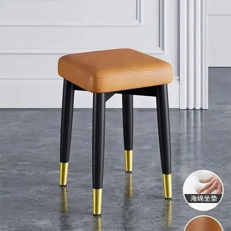 Modern low square stool with tan upholstered seat and black tapered legs with gold caps on Tampa Home & Garden Store
