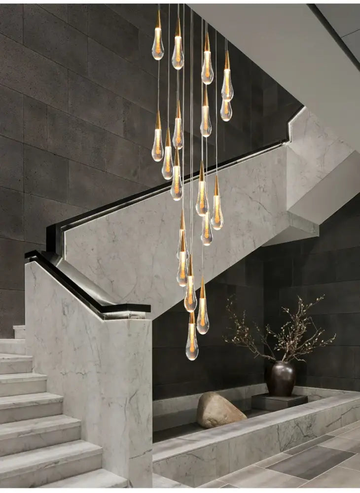 Gold teardrop chandelier with glass pendants on thin wires, cascading over marble stairs on Tampa Home & Garden Store