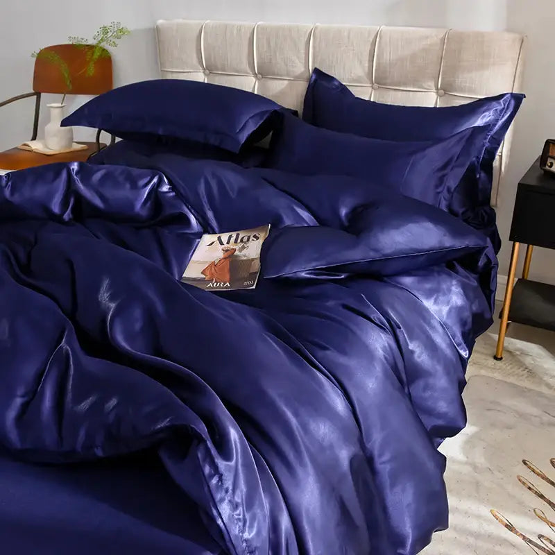 Navy blue silk duvet cover set with matching pillowcases on a beige tufted headboard bed on Tampa Home & Garden Store