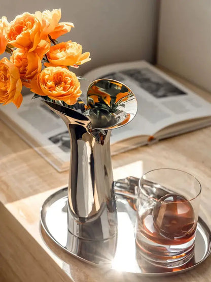 Silver stainless steel vase with curved neck and orange flowers on a mirrored tray on Tampa Home & Garden Store