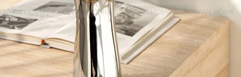 Silver stainless steel vase by Decorbites on a wood table with an open magazine nearby on Tampa Home & Garden Store