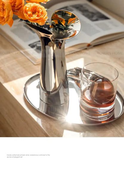 Silver stainless steel vase from Decorbites with orange roses on a round mirrored tray on Tampa Home & Garden Store