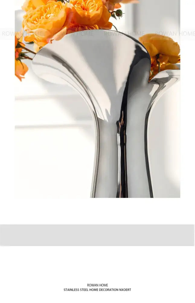 Silver stainless steel vase by Decorbites with curved sculptural form holding orange flowers on Tampa Home & Garden Store