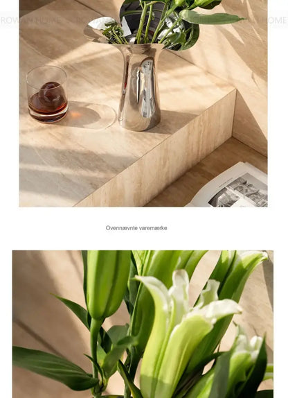 Silver stainless steel vase by Decorbites with green stems on a beige stone surface on Tampa Home & Garden Store