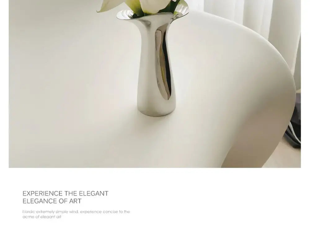 Silver stainless steel vase by Decorbites with white flowers on a white surface on Tampa Home & Garden Store