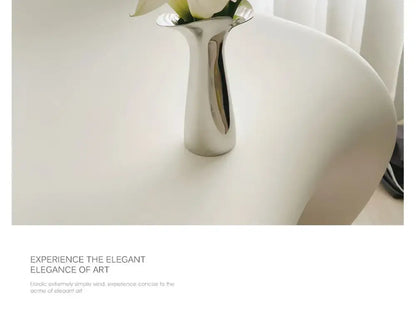 Silver stainless steel vase by Decorbites with white flowers on a white surface on Tampa Home & Garden Store