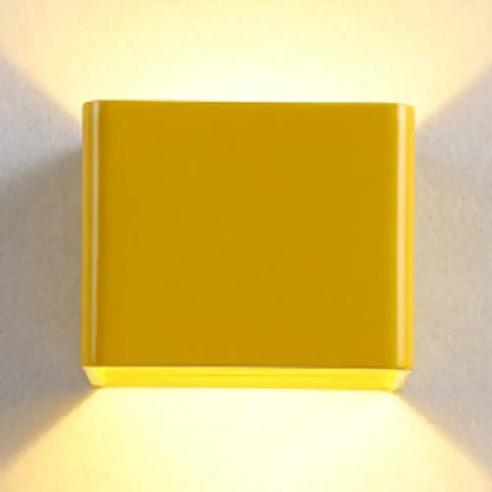 Yellow cube wall sconce with glossy finish emitting warm glow from top and bottom on Tampa Home & Garden Store