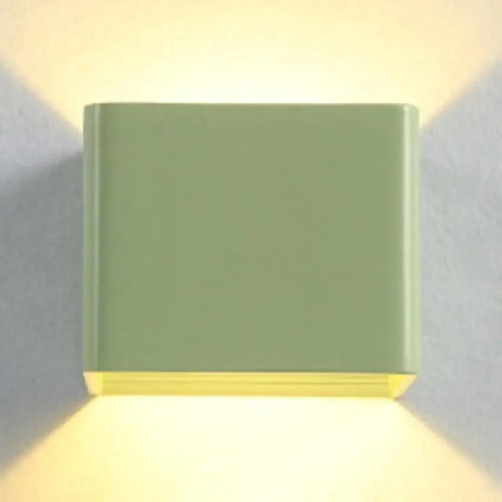 Black cube wall sconce with matte finish, emits warm yellow uplight and downlight on Tampa Home & Garden Store