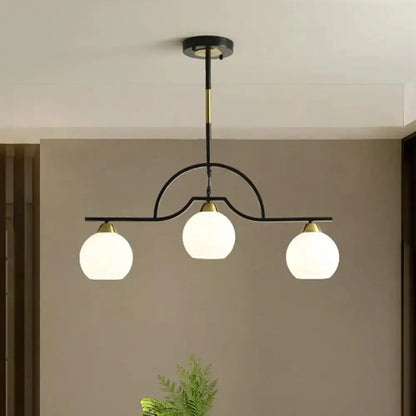 Modern black and brass arched pendant light with three white glass globes on Tampa Home & Garden Store