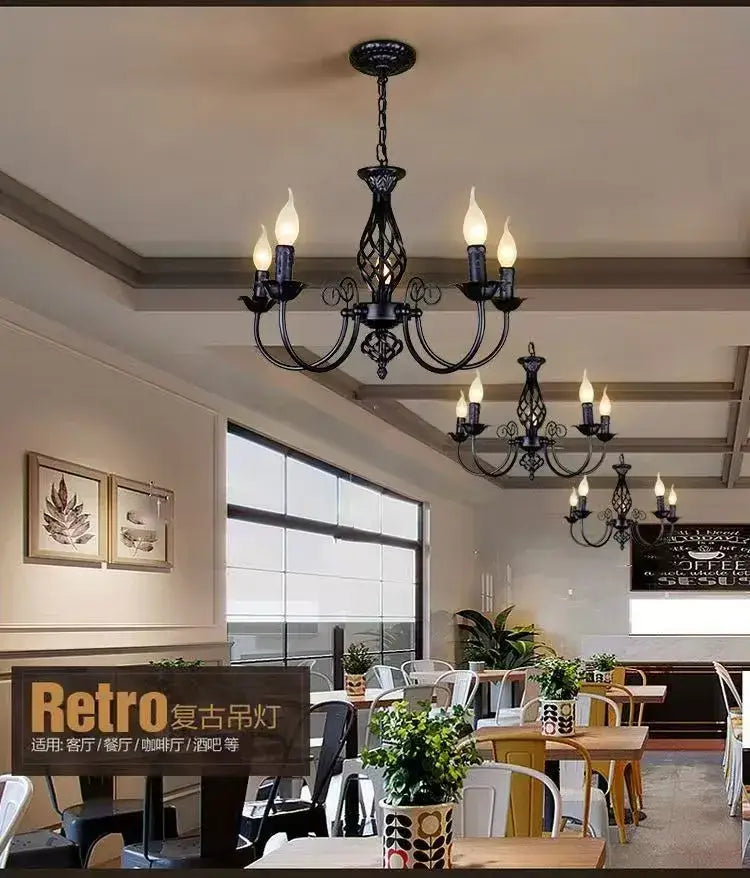 Two black iron scroll chandeliers with candle bulbs in a retro dining area by Decorbites on Tampa Home & Garden Store