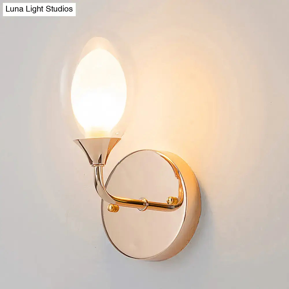 Gold wall sconce with circular backplate and curved arm supporting a candle bulb on Tampa Home & Garden Store