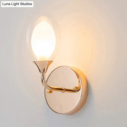 Gold wall sconce with circular backplate and curved arm supporting a candle bulb on Tampa Home & Garden Store