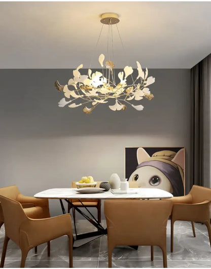 Decorbites Gold Ginkgo LED Chandelier with leaves over a round marble dining table and tan chairs on Tampa Home & Garden Store