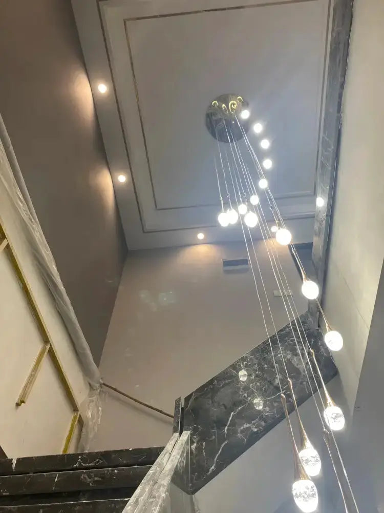 Decorbites modern gold LED crystal chandelier cascading pendant above marble stairs on Tampa Home & Garden Store