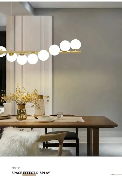 Modern gold linear LED chandelier dining room pendant light by Decorbites with globe orbs along a gold bar on Tampa Home & Garden Store