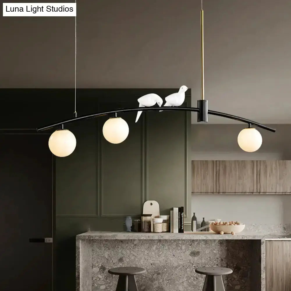 Pendant light with curved black arm and brass accents, three milk glass globes and bird decor on Tampa Home & Garden Store