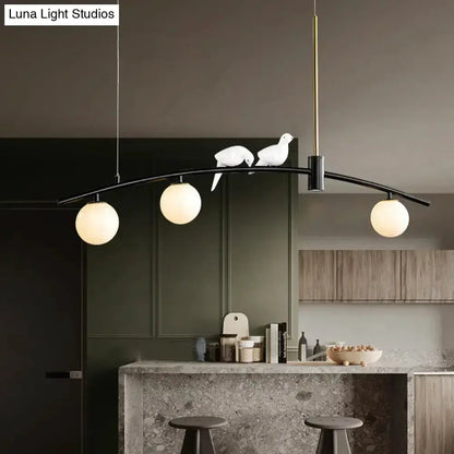 Pendant light with curved black arm and brass accents, three milk glass globes and bird decor on Tampa Home & Garden Store