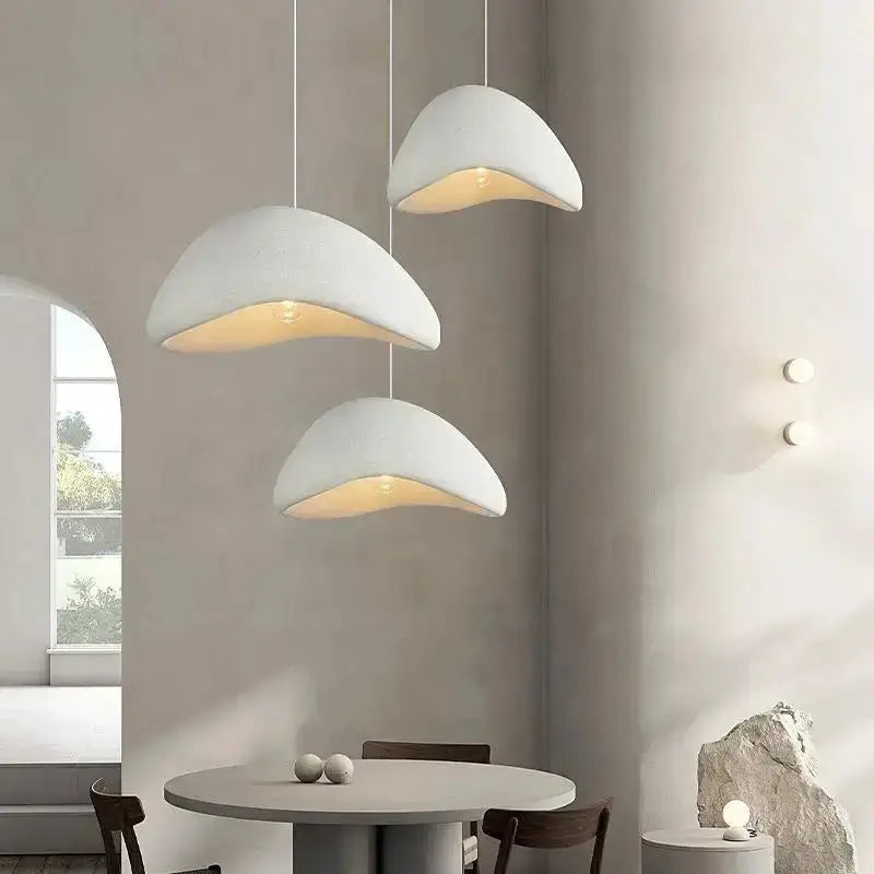 Three modern gray dome pendant lights by Decorbites with warm yellow interior over dining table on Tampa Home & Garden Store