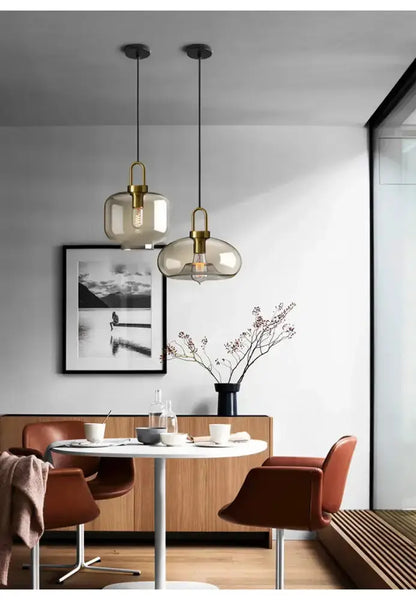Pendant light set with modern smoked glass and brass hardware (2) above a white round dining table on Tampa Home & Garden Store