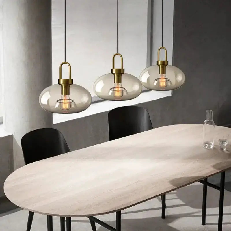 Modern smoked glass and brass pendant light set by Decorbites with 3 domes over a dining table on Tampa Home & Garden Store