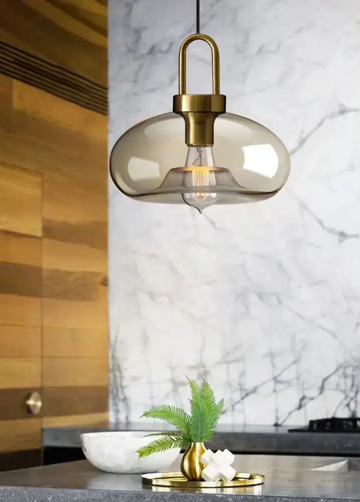 1 smoked-glass and brass pendant light over kitchen island; 1 brass vase with fern on counter on Tampa Home & Garden Store