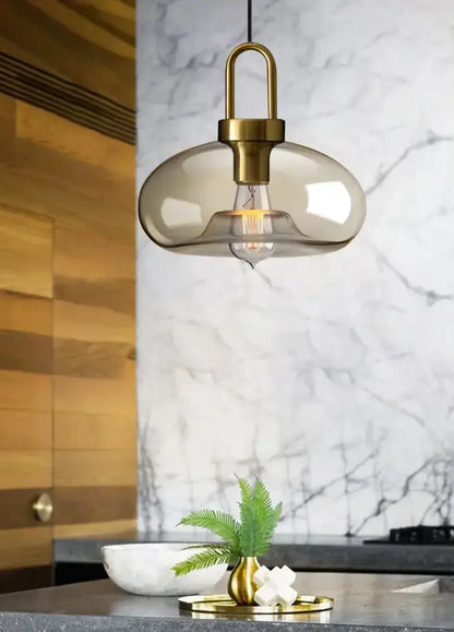 1 smoked-glass and brass pendant light over kitchen island; 1 brass vase with fern on counter on Tampa Home & Garden Store
