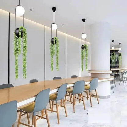 Modern Decorbites black and white planter pendant lights with trailing greenery over a wood table on Tampa Home & Garden Store