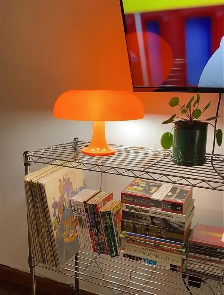 Black LED Mushroom Lamp table lamp with orange glow on a metal wire shelf beside books on Tampa Home & Garden Store