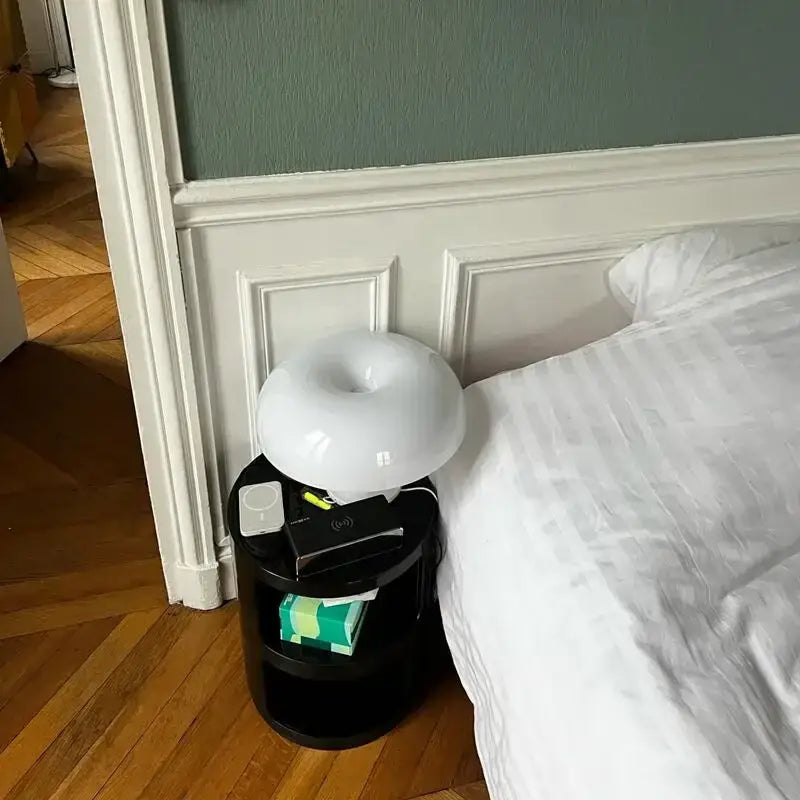 Decorbites Black LED Mushroom Lamp on round black bedside table beside a white duvet bed on Tampa Home & Garden Store
