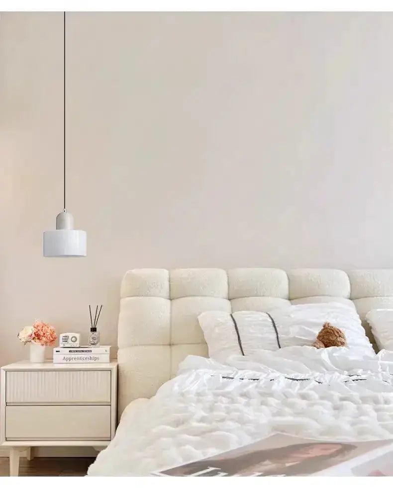 White glass pendant light above a cream tufted headboard with a beige nightstand on Tampa Home & Garden Store