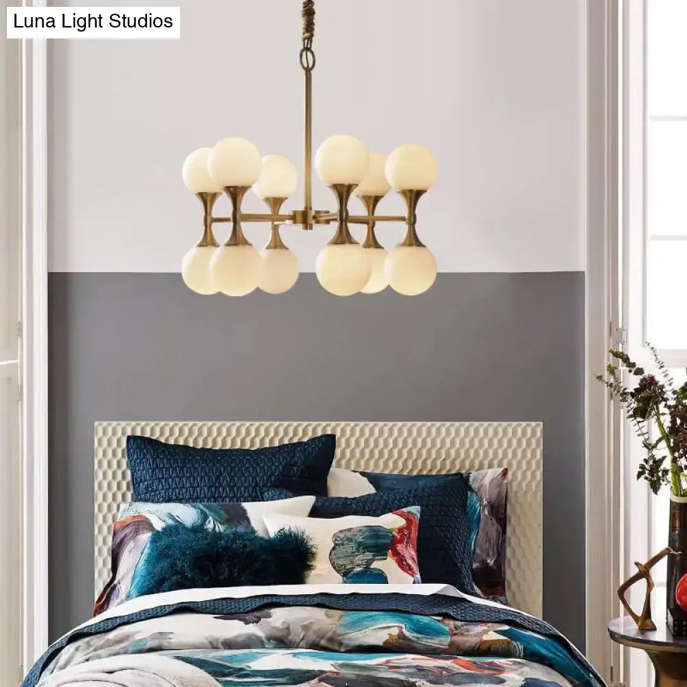 Brass globe chandelier with eight frosted glass globes and central rod in a modern bedroom on Tampa Home & Garden Store