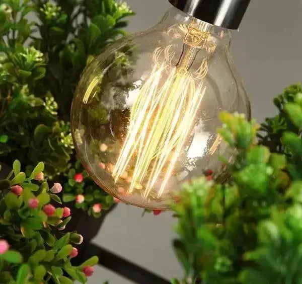Industrial black metal planter light pendant with glass globe and Edison bulb amid greenery on Tampa Home & Garden Store