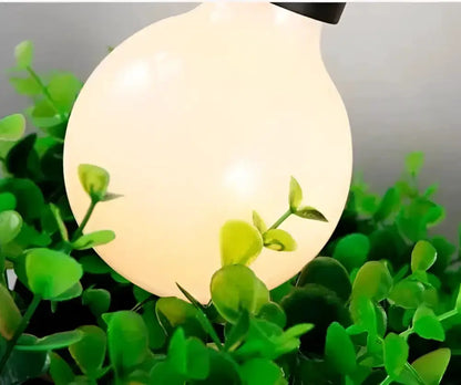 Industrial black metal planter light pendant chandelier with glowing orb among green foliage on Tampa Home & Garden Store