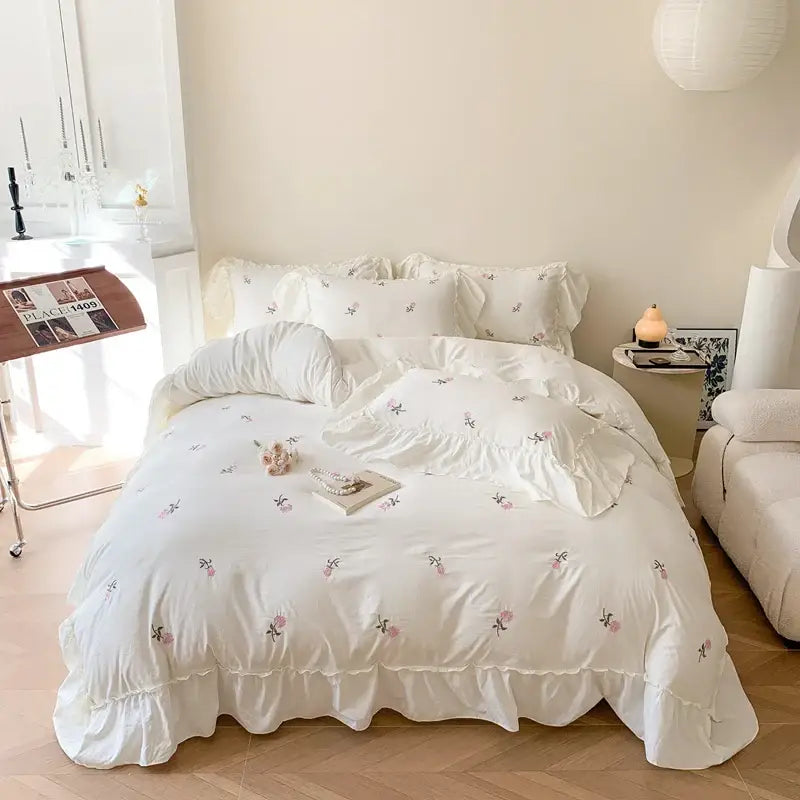 White ruffled duvet set with pink floral embroidery on bed on Tampa Home & Garden Store
