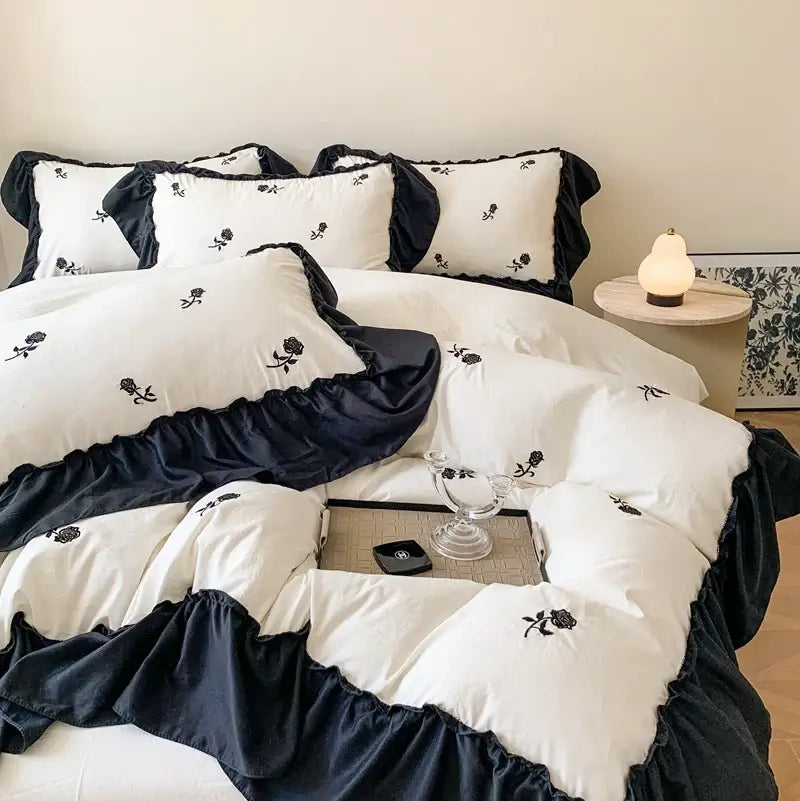 White Ruffled Duvet Set by Decorbites with black ruffle trim and rose embroidery on bed on Tampa Home & Garden Store