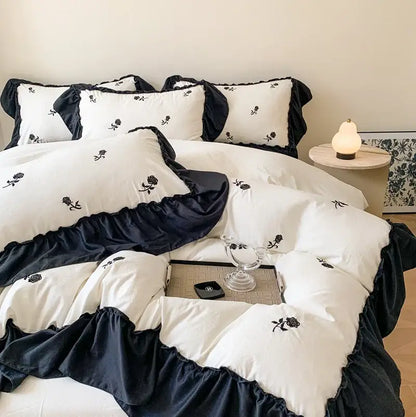 White Ruffled Duvet Set by Decorbites with black ruffle trim and rose embroidery on bed on Tampa Home & Garden Store