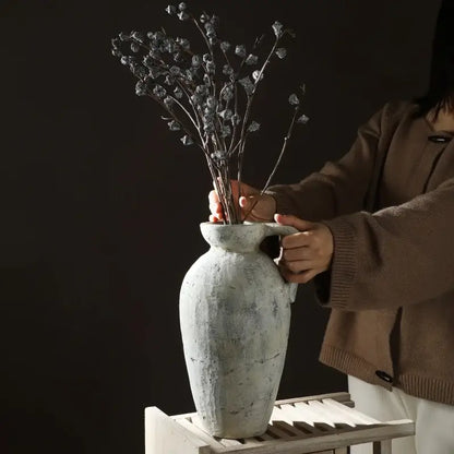 White ceramic pottery vase by Decorbites with weathered gray finish held against dark background on Tampa Home & Garden Store