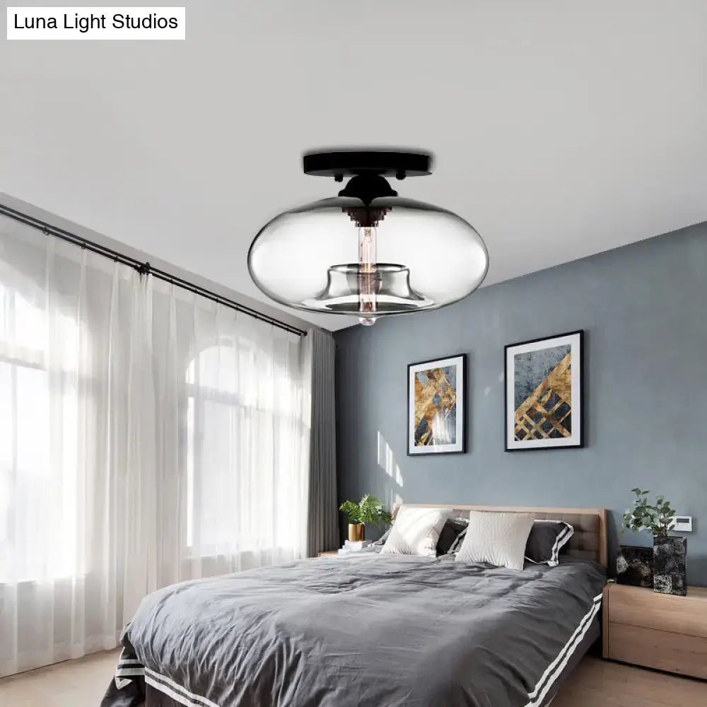 Glass oval flush mount ceiling light with clear glass shade and black canopy in a gray bedroom on Tampa Home & Garden Store