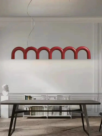 Red u-shaped chandelier with connected arches suspended over a dining table on Tampa Home & Garden Store