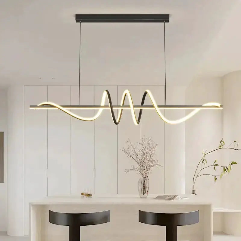 Sleek wavy pendant light in brushed metallic finish over white kitchen island on Tampa Home & Garden Store