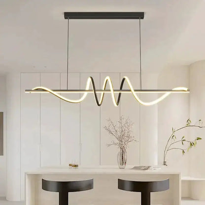 Sleek wavy pendant light in brushed metallic finish over white kitchen island on Tampa Home & Garden Store